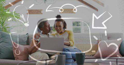 Intergenerational women sharing laptop on sofa, learning together and bonding at home