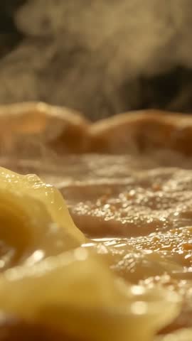 Vertical video heating ravioli in frying pan with bubbling sauce and rising steam