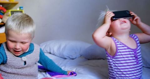 Joyful siblings playing in bright bedroom environment