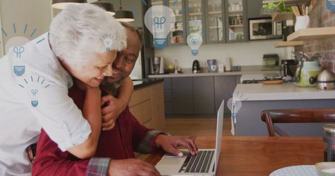 Senior Couple Embracing with Light Bulb Graphics in Modern Kitchen