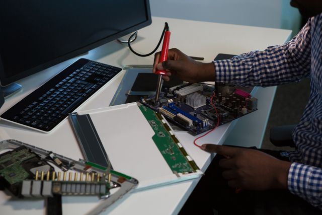 Computer engineer repairing motherboard at desk in office