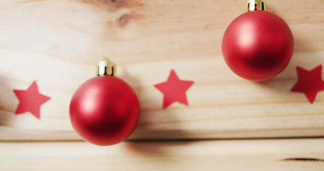 Image of red baubles and stars on pale wooden background. christmas, tradition and celebration concept.