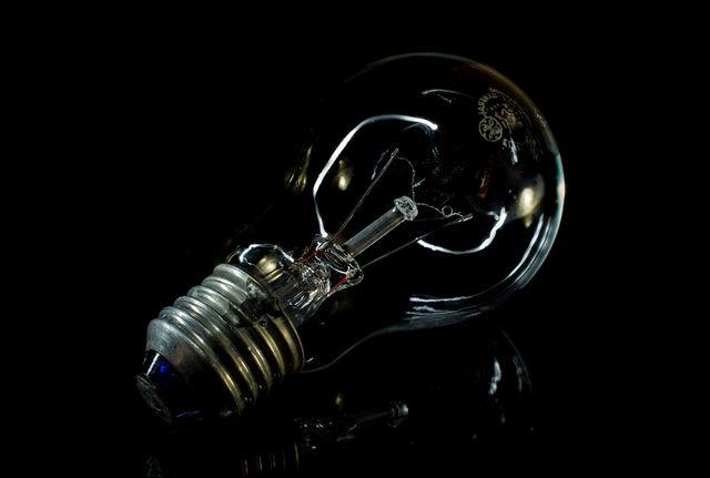Light bulb lying on black surface. Focus on broken filament and transparent glass. Shows fragility and failure. Useful for representing life challenges, power outage, or creative concepts.