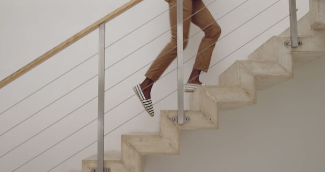 Person climbing modern stairs in a bright indoor setting. The focus on the steps and railing adds a minimalist aesthetic to the scene.