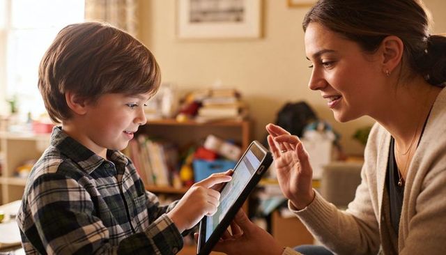 Mother and son exploring educational tablet together in cozy home, learning, bonding