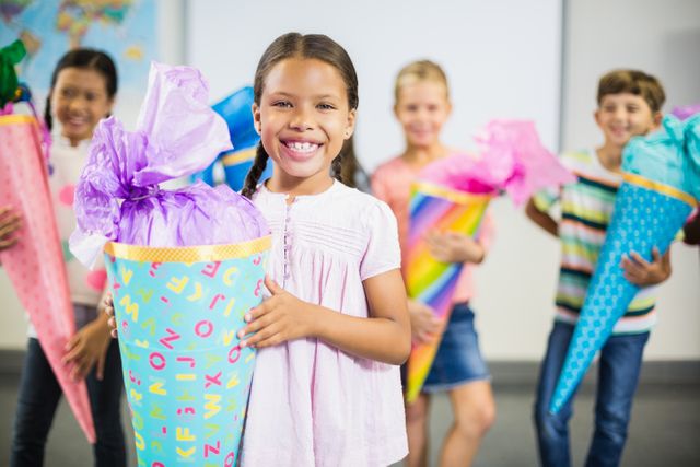 Happy schoolgirl holding gift in classroom at school