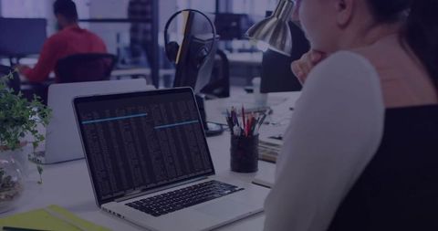 Focused developer studying terminal output on laptop in modern open office with desk plant