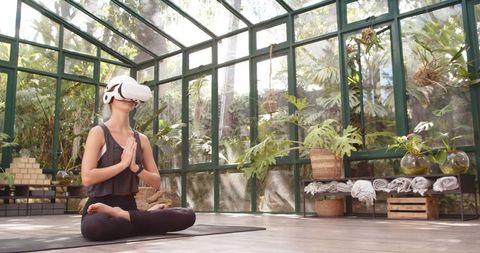 Woman meditates with vr headset in serene glass house