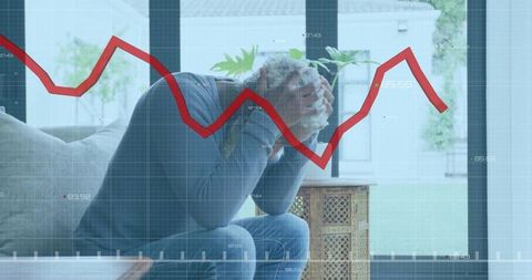 Stressed man with red decline graph overlay at home