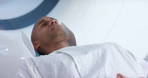 Male patient undergoing mri scan lying supine in modern clinical scanner bore