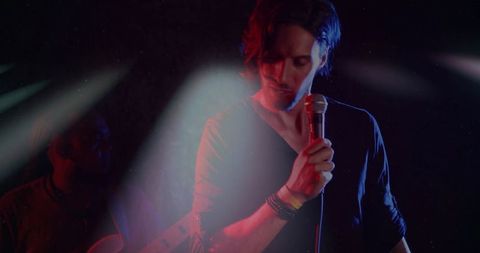 Singer performing under spotlights on stage in moody atmosphere