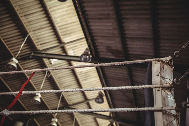 This image captures the ropes of a boxing ring in an industrial-style gym. Ideal for use in fitness blogs, sports training websites, gym advertisements, and articles about boxing or fitness training.