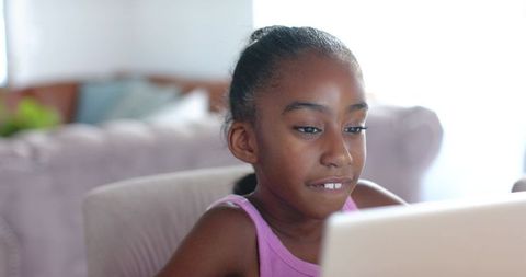 African american girl using laptop at home learning online studying concentrating