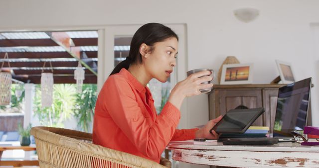 Biracial woman using laptop and working in living room. Beauty, health and female spa home concept.