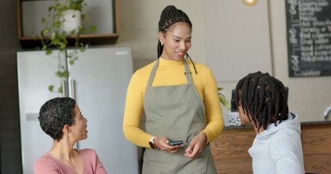 Cafe server taking order with smartphone while customers chat at cozy counter