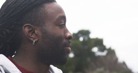 African American man gazing into distance, profile with dreadlocks and hoop earring