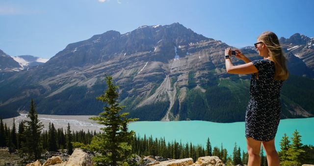 Caucasian female tourist couple standing on cliff and taking a photo by sunny lake. Summer, vacations, traveling, technology, photography and active lifestyle, unaltered.