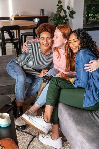 Diverse Female Friends Embracing on Sofa in Living Room