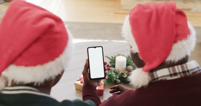 Two People Wearing Santa Hats Using Smartphone During Christmas - Download Free Stock Images Pikwizard.com