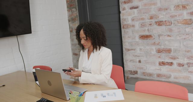 Businesswoman Checking Smartphone While Working on Laptop in Office - Download Free Stock Images Pikwizard.com