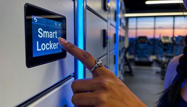 Woman pressing smart locker touchscreen at gym wearing silver ring and sleeveless top