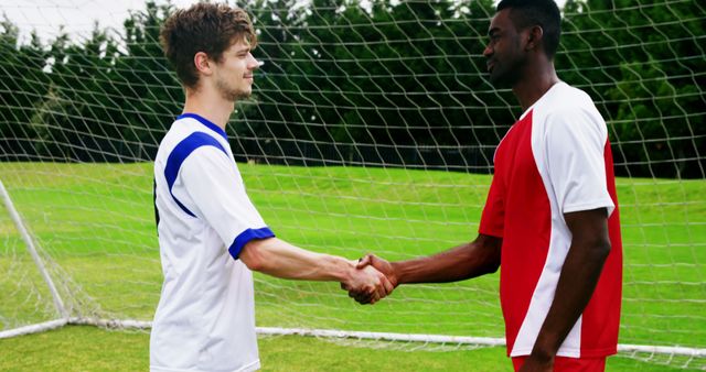 Two young adult soccer players, one Caucasian and one African American, are shaking hands on the field, with copy space. Their sportsmanship showcases the respectful and friendly spirit of competition in sports.