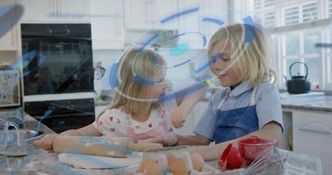 Siblings baking together in sunlit kitchen wearing colorful aprons kneading dough