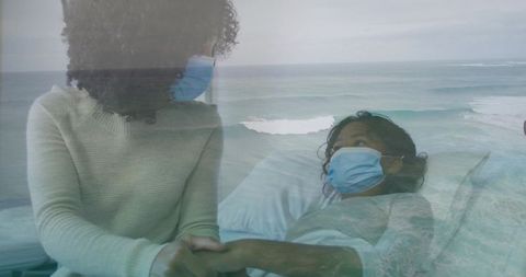 Holding hand, supporting hospitalized child wearing face mask beside ocean view, family healing