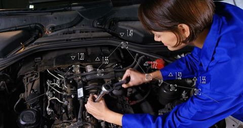 Female mechanic repairing car engine with ratchet wrench and digital diagnostic overlays