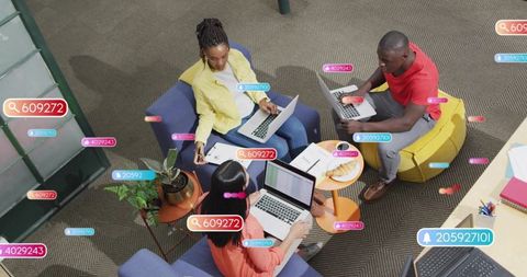Team of three collaborating on laptops in modern lounge with ui notification overlays