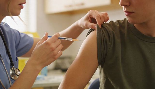 Nurse administering vaccine to patient in clinic close-up arm injection with syringe