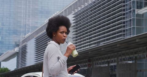 Businesswoman Walking with Coffee and Smartphone in Urban Cityscape