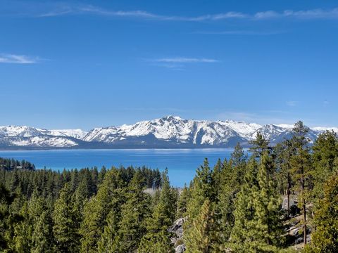 Snow-capped mountains reflected in clear lake with lush forest in foreground