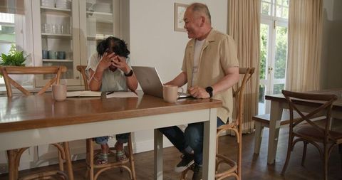 Senior Couple Collaborating on Laptop at Dining Table