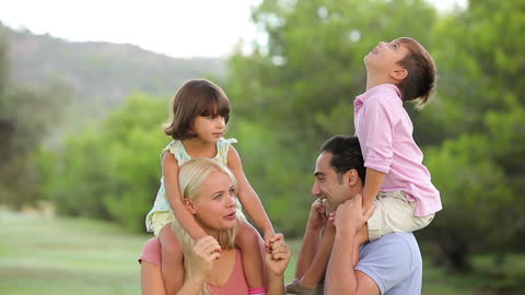 Joyful Family Enjoying a Day in Park with Kids on Shoulders