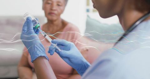 Nurse drawing vaccine into syringe during home care visit for elderly patient