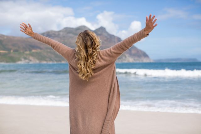 Rear view of mature woman with arms outstretched standing on the beach