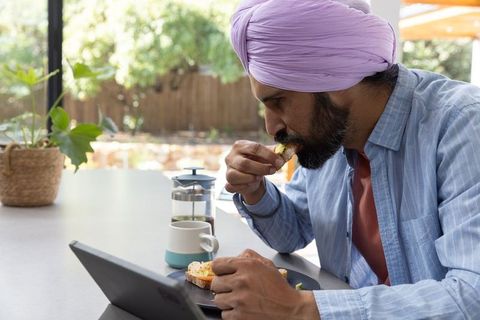 Man with Purple Turban Eating Avocado Toast at Home Kitchen Table