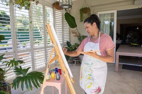 Woman painting peacefully on sunlit veranda