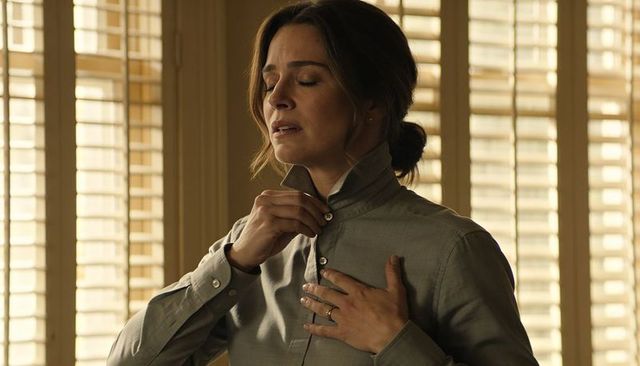Buttoning shirt woman touching chest showing ring warm natural light window shutters