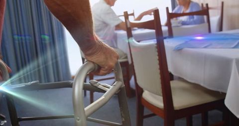 Elderly man using walker in sunlit dining room