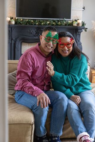 Cheerful Senior Couple in Festive Glasses Relaxing on Cozy Sofa