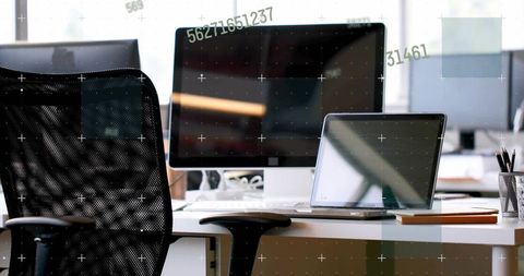Modern workstation featuring desktop and laptop with data overlay and ergonomic chair