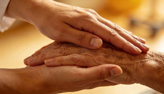Holding and comforting elderly hands, offering gentle caregiver support and human warmth