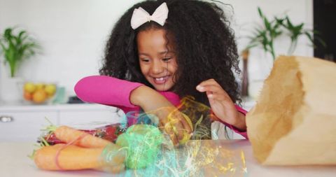 Smiling girl unpacking fresh produce from brown paper bag on bright home kitchen counter