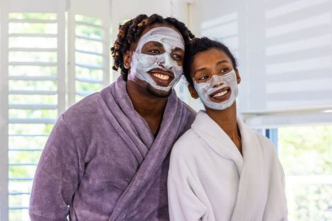 African american couple enjoying home spa night with facial masks and plush robes