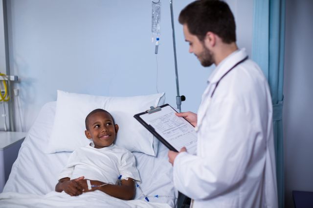 Doctor reading patient's medical report while young patient lying in hospital bed. Ideal for healthcare, medical services, pediatric care, and hospital-related content. Useful for illustrating doctor-patient interactions, medical examinations, and hospital environments.