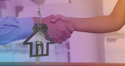 Handshake agreement over house keys symbolizing real estate deal