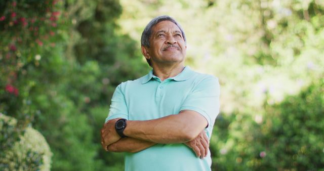 Image of happy biracial senior man looking at camera in garden. active retirement lifestyle and spending time outdoors.