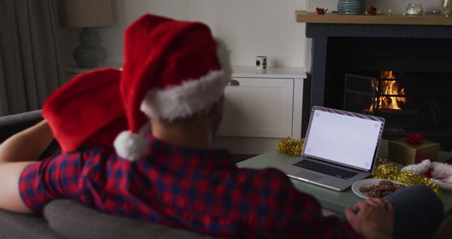 Back view of caucasian couple wearing santa hats using laptop with copy space on screen - Download Free Stock Photos Pikwizard.com